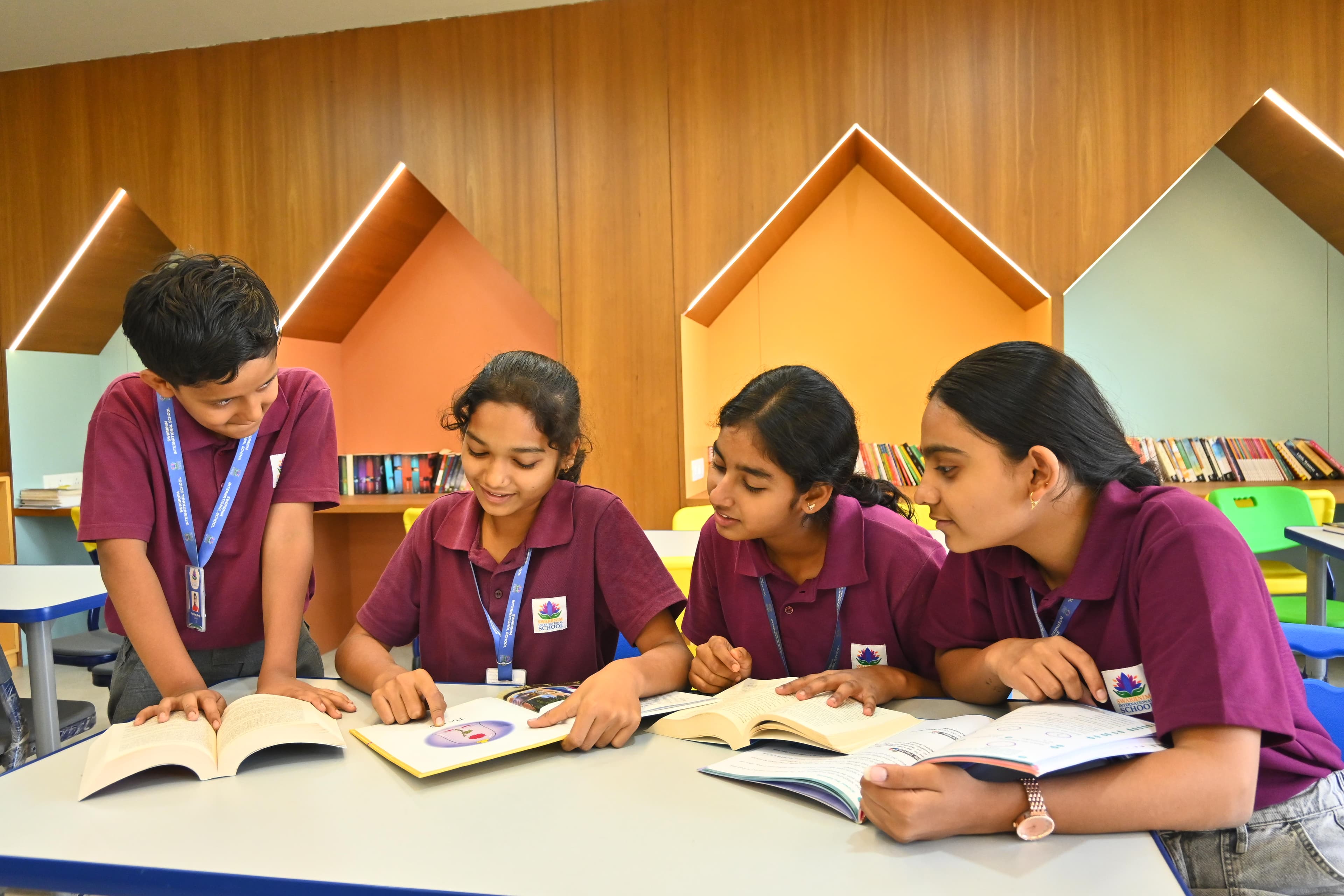 Four primary students happily reading on colourful bean bags in the reading nook